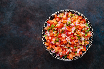 Pico de Gallo on a dark background. Homemade pico de gallo with tomatoes, peppers, jalapenos and red onions. Top view. Copy space