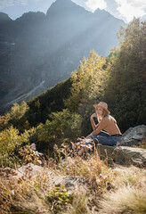 Naklejka na ściany i meble Young woman on a hiking trip sitting on a rock