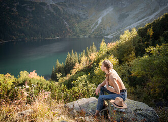 Naklejka premium Young woman on a hiking trip sitting on a rock