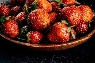 Red strawberries on a dark board.