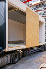 Prefabricated wooden building module on a truck, ready to beeing set into the building by a crane. - obrazy, fototapety, plakaty