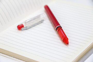 Red Pen and Pen Lid on a Blank Page of a Notebook