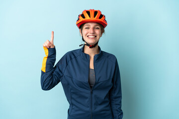 Young cyclist woman isolated on blue background pointing up a great idea - obrazy, fototapety, plakaty