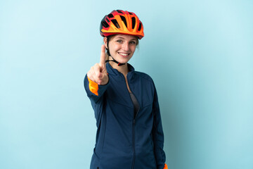 Young cyclist woman isolated on blue background showing and lifting a finger
