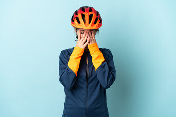 Young cyclist woman isolated on blue background with tired and sick expression