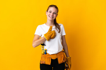 Young electrician woman isolated on yellow background giving a thumbs up gesture