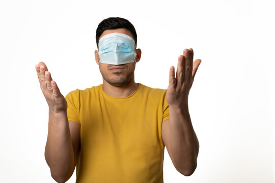 young man with blue mask on his eyes, tired, not protected from coronavirus, shrugging his shoulders. tired. white background - stock photo