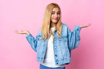 Young Uruguayan blonde woman over isolated pink background making doubts gesture