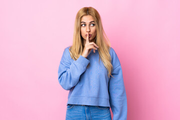 Young Uruguayan blonde woman over isolated pink background showing a sign of silence gesture putting finger in mouth
