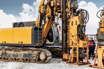 A powerful drilling rig for piling in winter at a construction site. Operation of the drilling rig...