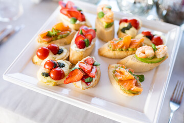 Bruschetta with tomatoes, mozzarella cheese and basil on a cutting board. Traditional italian appetizer or snack, antipasto. Caprese salad bruschetta. Top view with copy space.