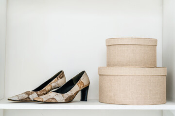 Storing women's shoes in a home closet. Shoes and round boxes are located on the shelf. Close-up