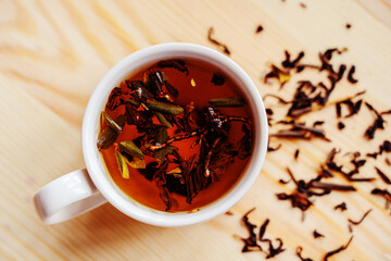 Brewed tea in a white cup. Freshly made ruby-colored drink. View from above