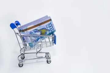 Tenge Kazakhstani money in a trolley on a white background.