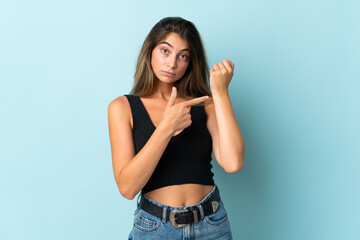 Young caucasian woman isolated on blue background making the gesture of being late