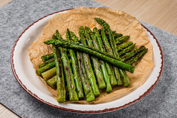 A plate of baked asparagus on parchment paper, close-up