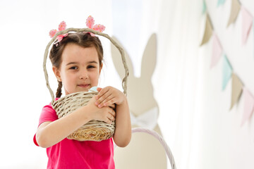 Cute little girl with bunny ears and basket of Easter eggs