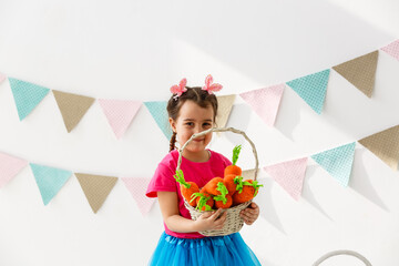 Getting ready to Easter. Lovely little girl holding an Easter egg and smiling with decoration in the background