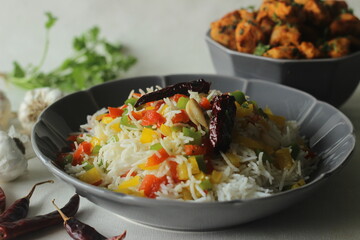 Steamed basmati rice tossed with sauteed bell peppers flavoured with red chillies and garlic. Served with chilli garlic chicken bites in a bowl