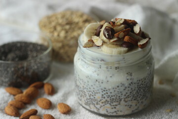 Overnight oats. Breakfast in a jar. Made by soaking rolled oats and chia seeds in milk served with chopped banana, almonds, Choco chips and a drizzle of honey.