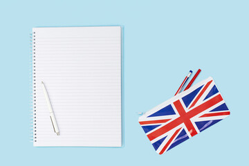 pencil case on desk with a pencil and a blank notebook and british english union jack flag. Flat lay with copy space. Education study or english language learning concept or travel and visa
