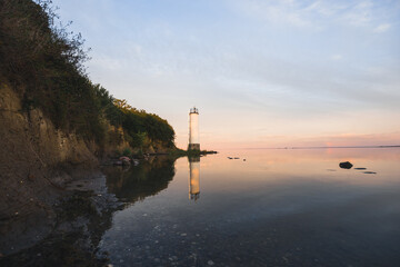 Fototapeta na wymiar Sonnenuntergang am Meer mit Spiegelung und Steinen am Leuchtturm Maltzien auf der Insel Rügen Ostsee in Deutschland