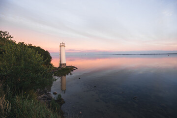 Fototapeta premium Sonnenuntergang am Meer mit Spiegelung und Steinen am Leuchtturm Maltzien auf der Insel Rügen Ostsee in Deutschland