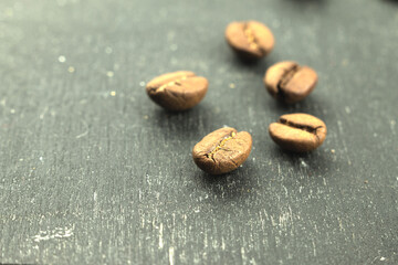 Five coffee beans on a wooden surface. Selective macro Photo