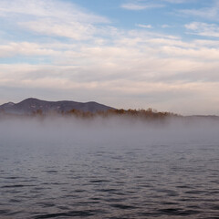 Fog on quiet lake water on a sunrise morning scene in Banyoles, Catalonia