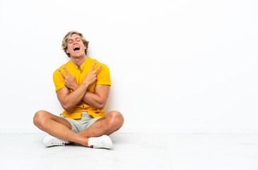 Young English man sitting on the floor smiling and showing victory sign