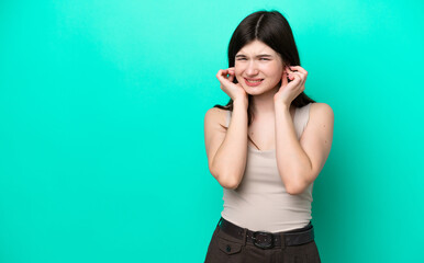 Young Russian woman isolated on green background frustrated and covering ears