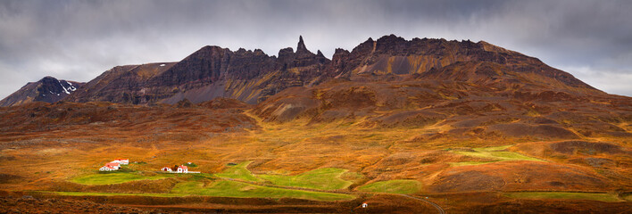 Panorama image of an autumn landscape with mountains, fields and farms in Iceland