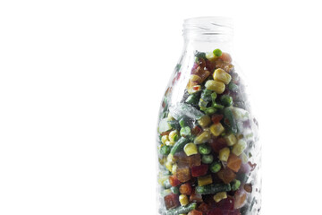 A glass bottle with a mixture of frozen vegetables in close-up.