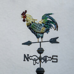 Weather vane with colored rooster on gray background