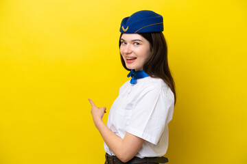 Airplane stewardess Russian woman isolated on yellow background pointing back