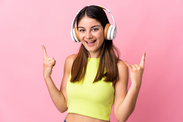 Fototapeta premium Young caucasian woman isolated on pink background listening music making rock gesture