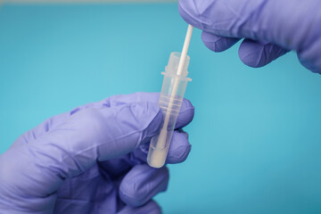 Doctor or nurse insertig a swab into an extraction tube, in the process of a antigen test