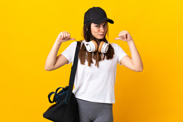 Young sport woman with sport bag isolated on yellow background proud and self-satisfied