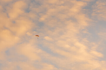 Para-plane flying high in the cloud sky at sunset  