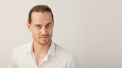 Young blonde bearded man looking in camera. Portrait of caucasian guy with trendy hairdo isolated over a white studio background with copy space