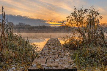 Fototapeta premium Sunrise over the river with wooden pier on beautiful October's morning