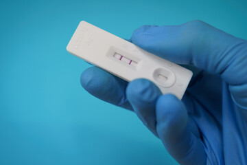 Obraz premium Closeup shot of a hand holding a positive antigen test