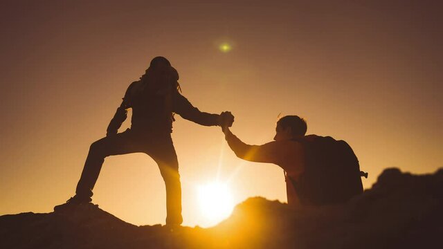 help team concept. team silhouette of two climber stretching a helping hand to a friend. business teamwork success concept. silhouette business travel tourists pull a sunlight helping hand