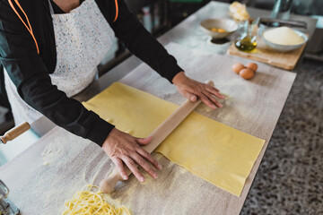 Close up female hands roll the dough preparing fresh homemade pasta