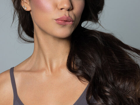 Close-up perfect lip makeup of a beautiful female mouth. Girl bites puffy sexy full lips. Macro photo detail of face. Perfectly clear skin, fresh lip makeup. Sweet pink lipstick. Valentines day style