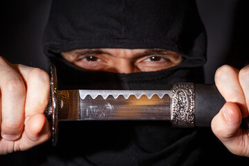 Ninja ready to fight, holding a Japanese sword. Photo of a warrior dressed in black clothes and...