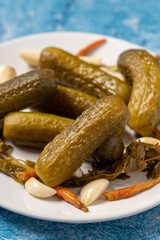 Pickled cucumbers on a blue background. Close-up of pickled cucumbers in a ceramic plate. close up. Story format