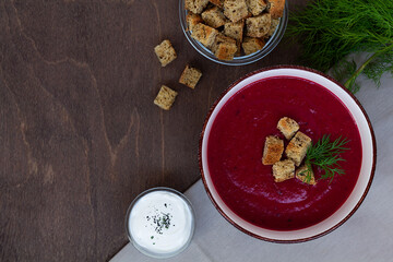 soup.vegetable soup with greens. Bowl of Beetroot cream soup with white cream and croutons on a brown wooden background. Healthy dietary lunch. Flat lay, top view. copy space