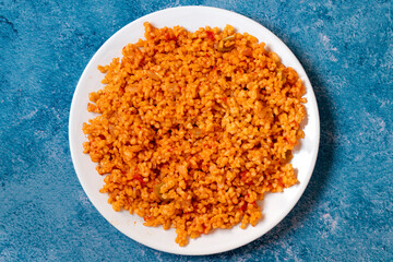Bulgur pilaf on a blue background. Close-up of Turkish food Bulgur Pilav in a ceramic plate. Top view