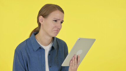 Young Woman Reacting to Loss on Tablet on Yellow Background